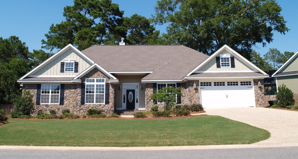 iew of a single family home with a stone exterior, driveway and lawn.